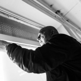 Virginijus Viningas simboliškai nusikabina parodos plakatą. Domo Rimeikos nuotr.